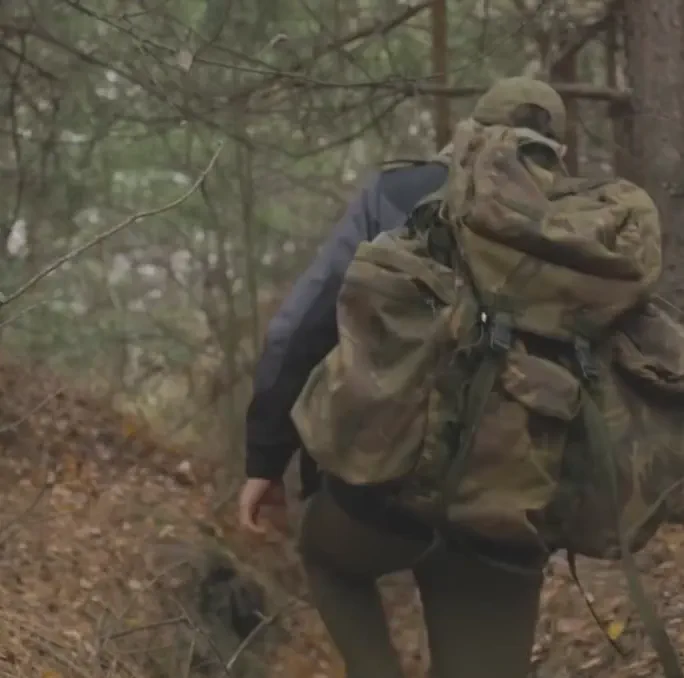 Hunter walking through the woods wearing a tactical backpack