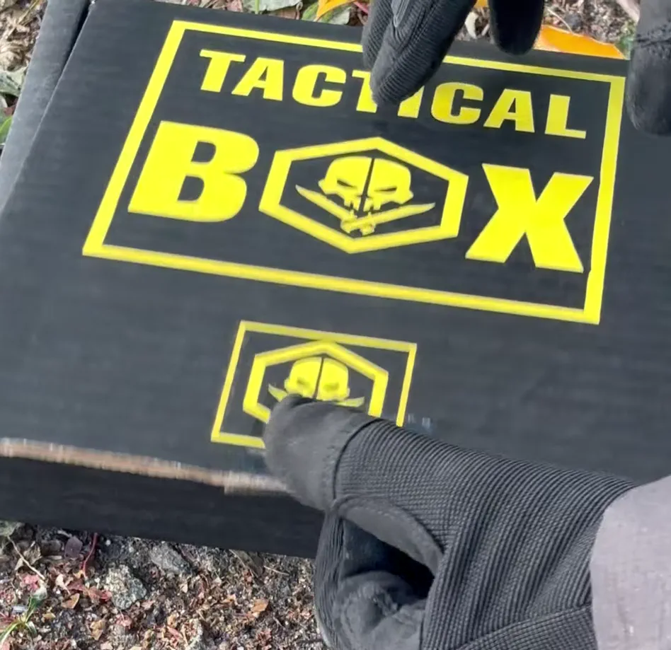 TacticalBox monthly membership box, black and yellow with skull and knife hexagon logo, as shown in the ad video