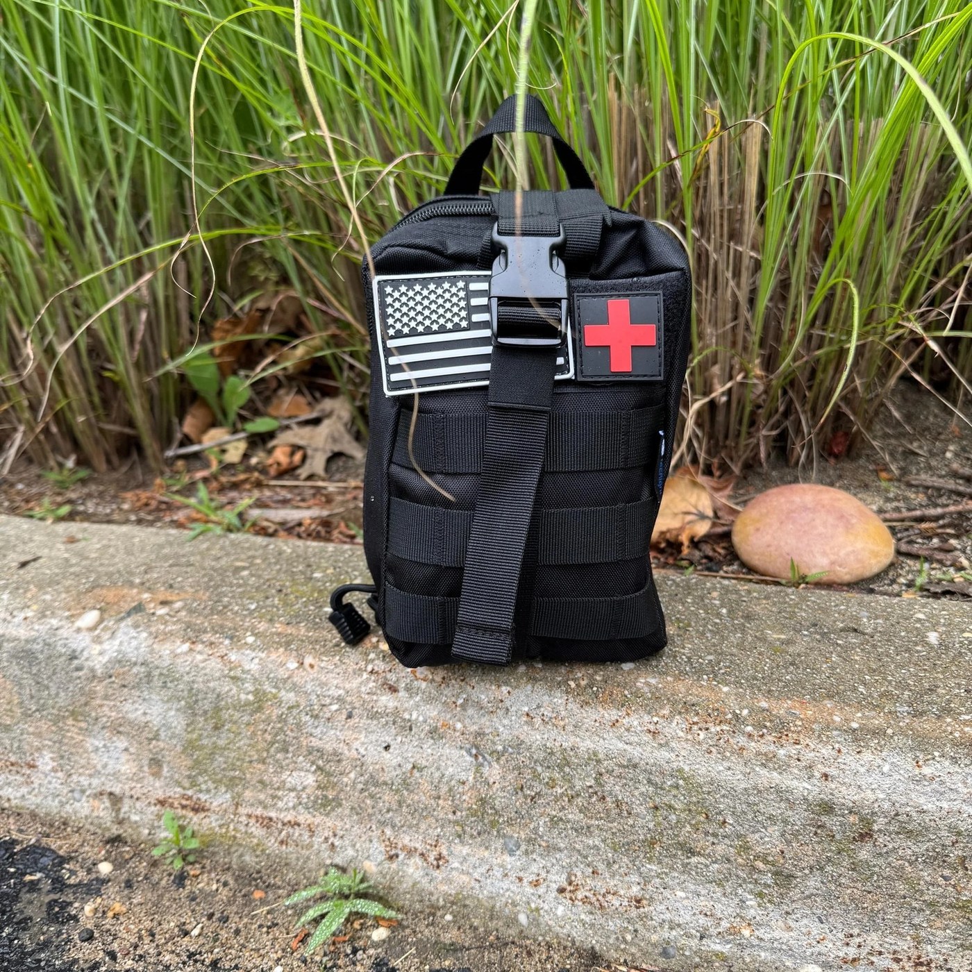 The Trauma First Aid Kit outdoors on a concrete kerb beside long grass