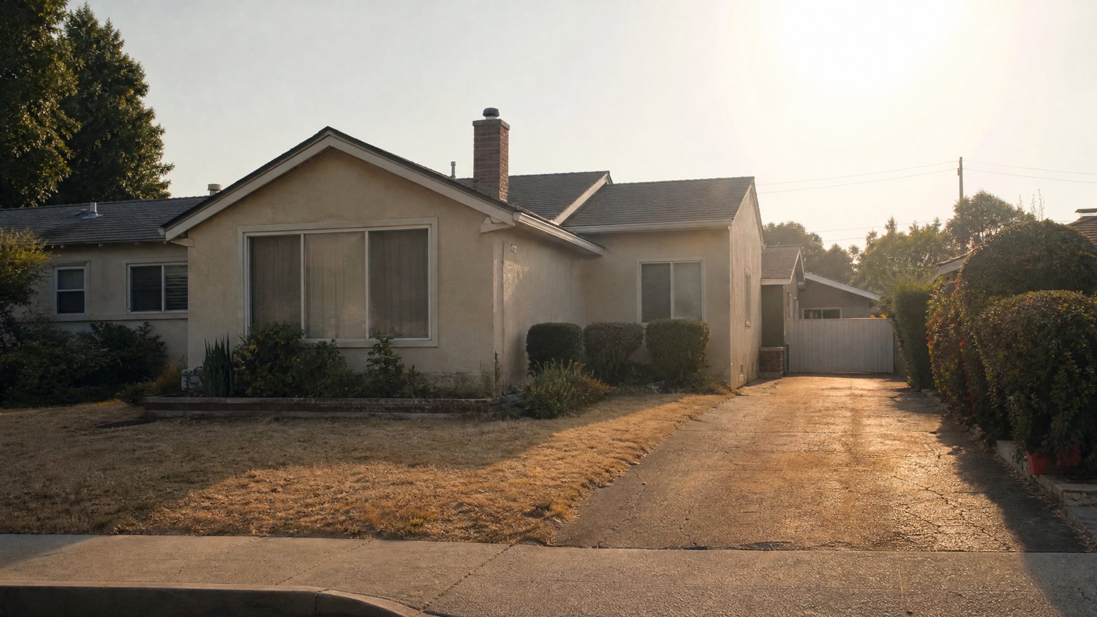 A suburban house on a hazy, hot afternoon with a dry lawn, heat shimmering over the driveway and curtains drawn